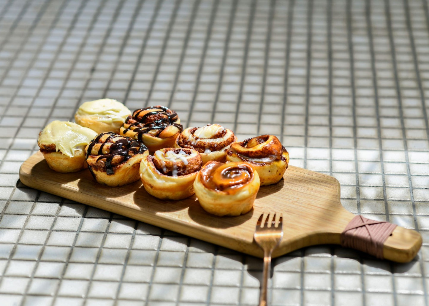 Wooden board with cinnamon rolls on a tiled floor