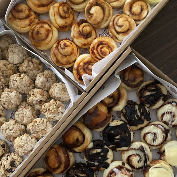 Assorted pastries including cinnamon rolls, cookies, and danishes in a box.