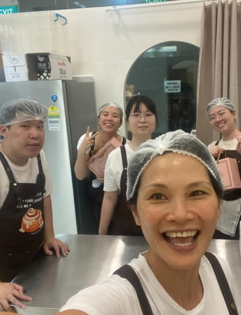 The GFF Crew  in a kitchen wearing hairnets and aprons, taking a selfie.