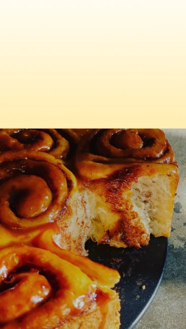 Close-up of a cinnamon roll with a bite taken out on a plate.