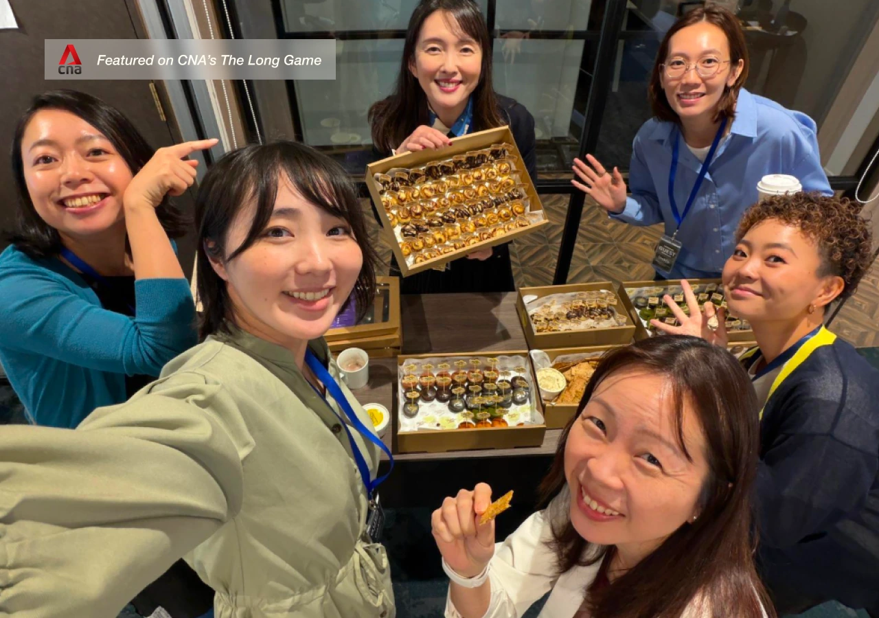 Group of people in an office posing with a display of Guilt Free Food cinnamon rolls and mochi muffins.